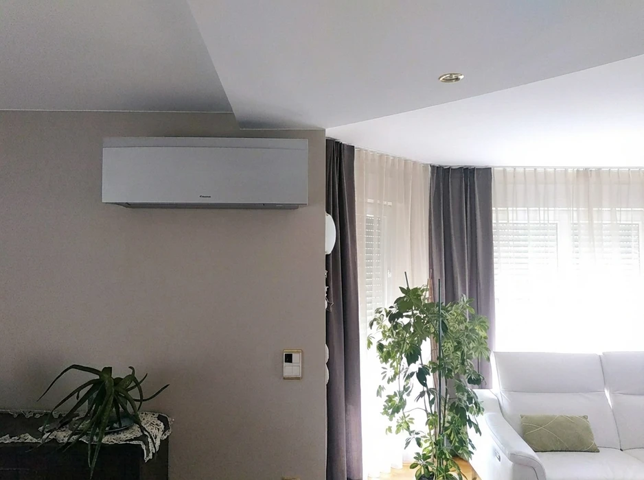Salon moderne avec unité intérieure de climatisation murale Daikin, modèle design silver, installée en hauteur sur mur beige