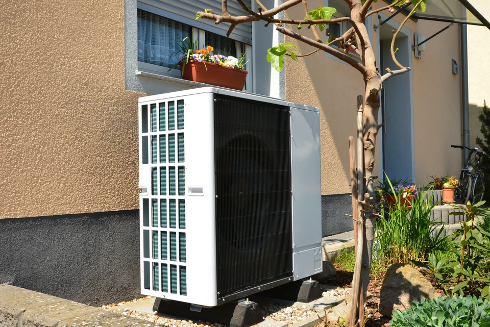 Extérieur résidentiel avec unité de climatisation/pompe à chaleur installée contre façade d'immeuble