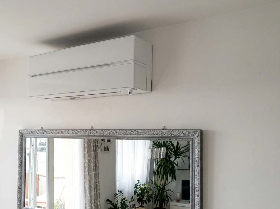 Intérieur résidentiel lumineux, mur blanc avec climatiseur mural en hauteur au-dessus d'un miroir encadré style baroque argenté