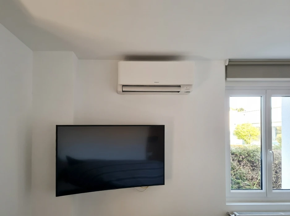 Intérieur blanc épuré avec climatiseur mural **Hitachi** en unité intérieure split-system, installé en hauteur