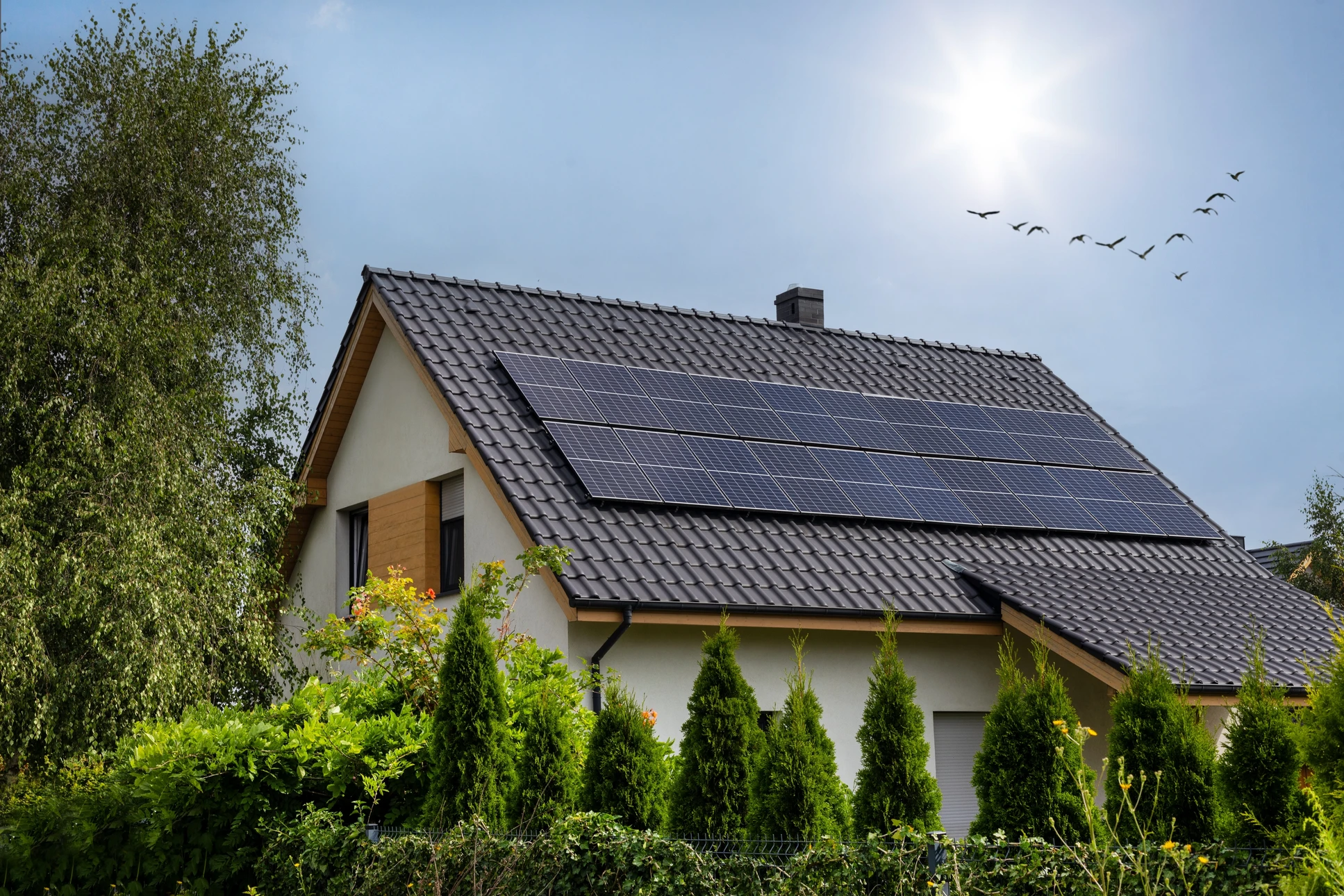 Technicien installant des panneaux solaires photovoltaïques sur toiture résidentielle sous ciel bleu